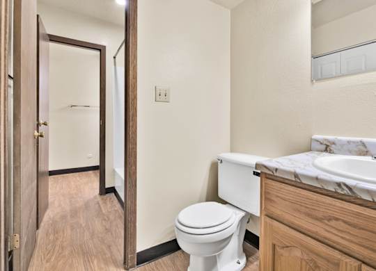 A white toilet sits in a bathroom next to a sink. at Winding Hills Apartments, Iowa