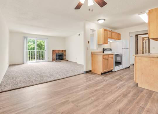 A living room with a fireplace and a kitchen area in the background. at Winding Hills Apartments, Davenport , IA, 52807
