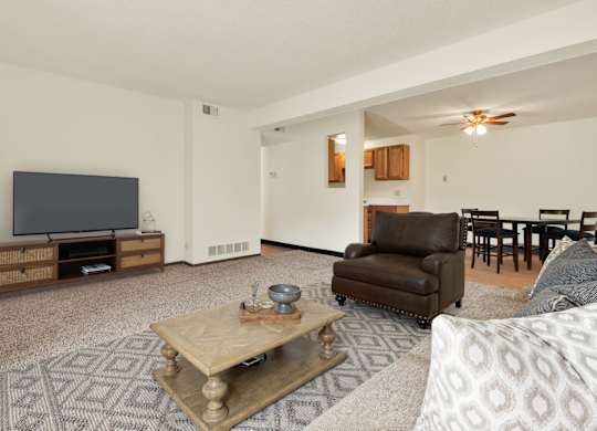 A living room with a brown leather chair and a wooden coffee table. at Winding Hills Apartments, Davenport , Iowa