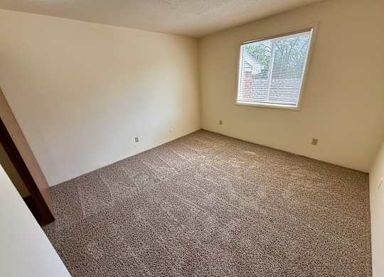 A room with a carpeted floor and a window. at Winding Hills Apartments, Davenport