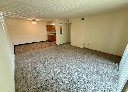 A room with a carpeted floor and a ceiling fan. at Winding Hills Apartments, Davenport  52807
