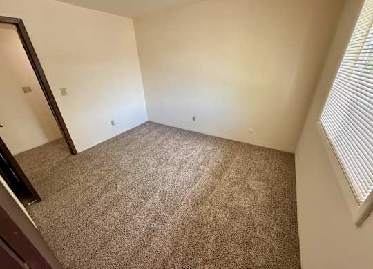 A room with carpeted floor and a window with blinds. at Winding Hills Apartments, Davenport , IA