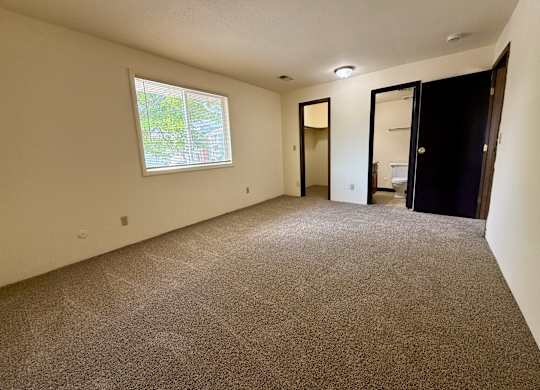 A room with a carpeted floor and a window. at Winding Hills Apartments, Davenport , IA, 52807