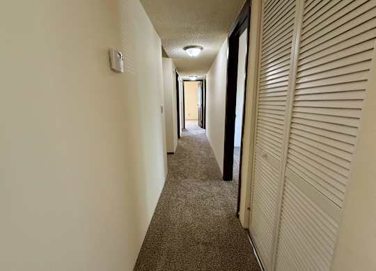 A long hallway with a carpeted floor and white walls. at Winding Hills Apartments, Davenport , IA