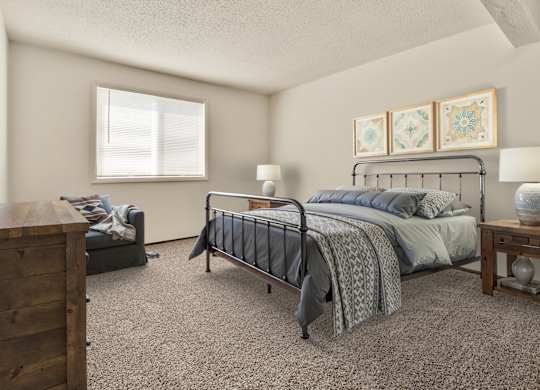 A bedroom with a bed, nightstand, and dresser. at Winding Hills Apartments, Davenport , IA