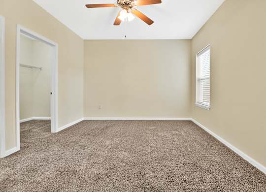 A room with a ceiling fan and carpeted floor. at Deer Valley Apartments, Silvis, IL, 61282