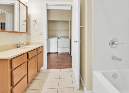 A bathroom with a white tub and a wooden vanity. at Deer Valley Apartments, Silvis