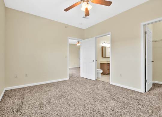 A room with a ceiling fan and carpeted floor. at Deer Valley Apartments, Silvis, IL, 61282