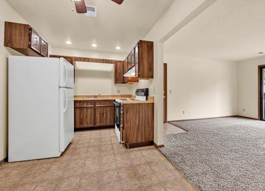 A kitchen with a white refrigerator and brown cabinets.at Windsor Crest Apartments, Davenport , Iowa