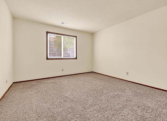 A room with a carpeted floor and a window.at Windsor Crest Apartments, Davenport 52807