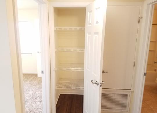 A white closet with shelves and a door.at Windsor Crest Apartments, Davenport 52807