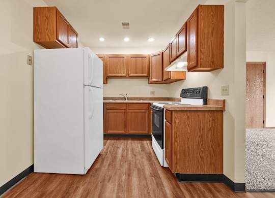 A kitchen with wooden cabinets and a white refrigerator.at Windsor Crest Apartments, Iowa