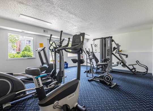 A gym with a row of treadmills and elliptical machines. at Winding Hills Apartments, Iowa, 52807
