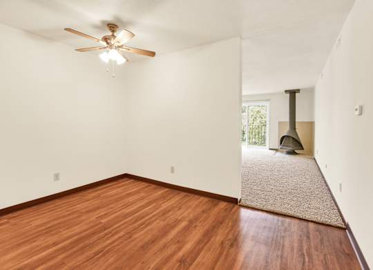 A room with a ceiling fan and wooden floors. at Indian Ridge Apartments, Davenport, 52807