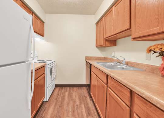 A kitchen with wooden cabinets and a white refrigerator. at Indian Ridge Apartments, Iowa