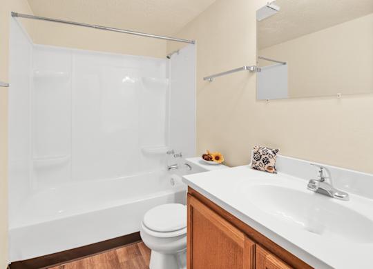 A white toilet sits next to a white sink in a bathroom. at Indian Ridge Apartments, Davenport, 52807
