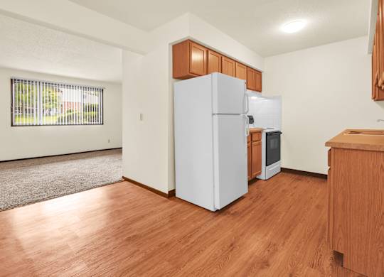 A white refrigerator is in a kitchen with wooden floors and cabinets. at Indian Ridge Apartments, Davenport, IA