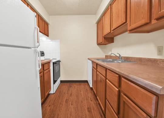 A kitchen with white appliances and wooden cabinets. at Indian Ridge Apartments, Iowa