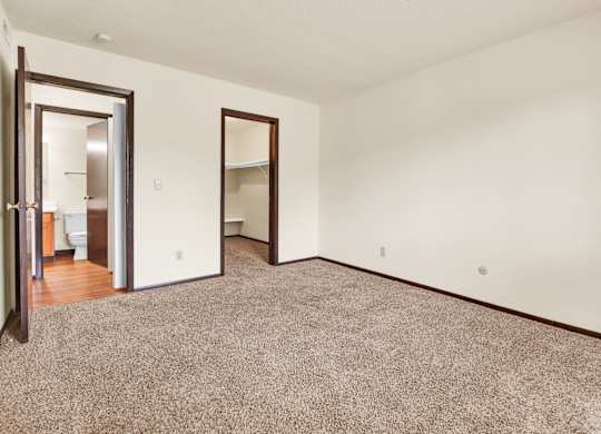 A room with a carpeted floor and two open doors. at Indian Ridge Apartments, Iowa, 52807