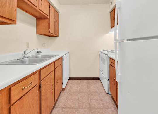 A kitchen with white appliances and wooden cabinets. at Indian Ridge Apartments, Davenport, IA, 52807