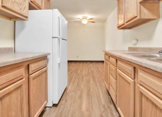 A kitchen with wooden cabinets and a white refrigerator. at Indian Ridge Apartments, Iowa