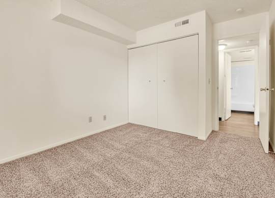 A room with a carpeted floor and a white door. at Indian Ridge Apartments, Davenport, IA