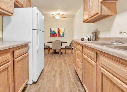 A kitchen with wooden cabinets and a white refrigerator. at Indian Ridge Apartments, Davenport, IA