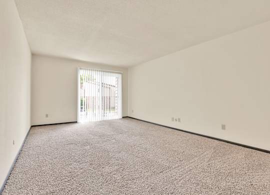 A room with a carpeted floor and a sliding glass door. at Indian Ridge Apartments, Davenport