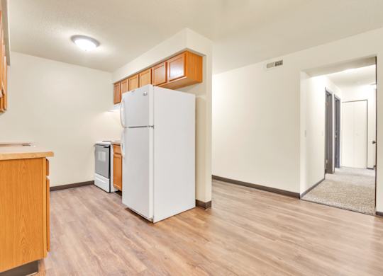A kitchen with a white refrigerator and wooden cabinets. at Indian Ridge Apartments, Davenport, IA, 52807