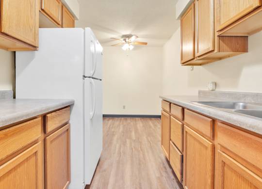 A kitchen with wooden cabinets and a white refrigerator. at Indian Ridge Apartments, Davenport, IA, 52807
