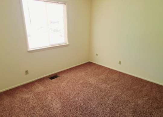 A room with a carpeted floor and a window. at Kimberly Club Apartments, Iowa, 52807
