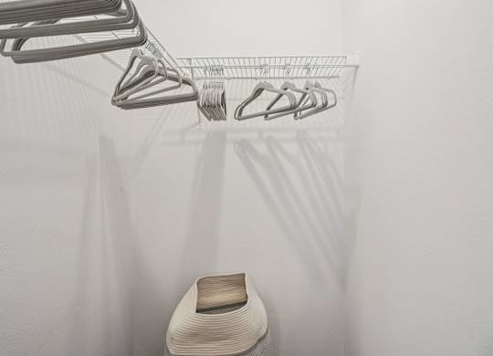 A white chair is under a clothes drying rack.