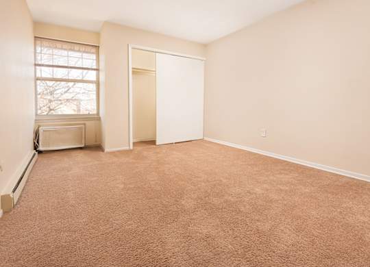 A room with a brown carpet and a window.