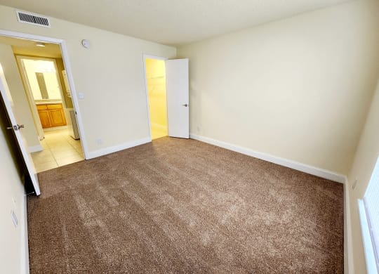 an empty living room with carpeting and a door to a bathroom at Sunscape Apartment Homes, Florida, 33613