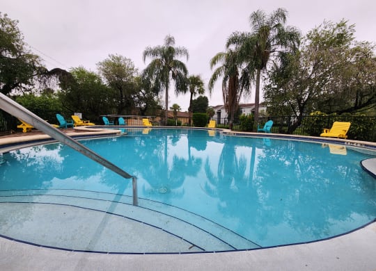 a swimming pool with palm trees and yellow chairs around it at Sunscape Apartment Homes, Tampa, Florida