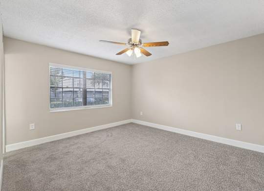 A room with a ceiling fan and a window.