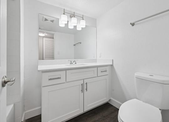 A white bathroom with a toilet, sink, and mirror.