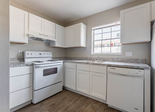 A white kitchen with a stove, oven, dishwasher, and refrigerator.
