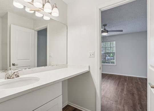 A bathroom with a white sink and mirror.