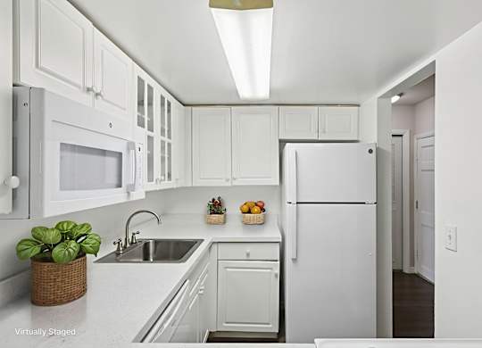 A white kitchen with a refrigerator, sink, and microwave.