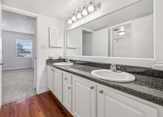 A bathroom with a sink, mirror, and wooden floors.