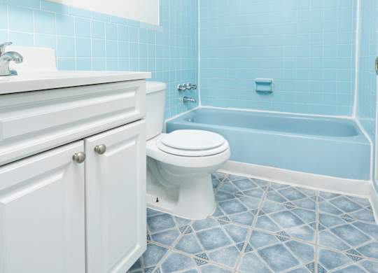 A white toilet in a blue tiled bathroom.