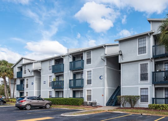 an apartment building with a parking lot and palm trees at Sunscape Apartment Homes, Florida, 33613