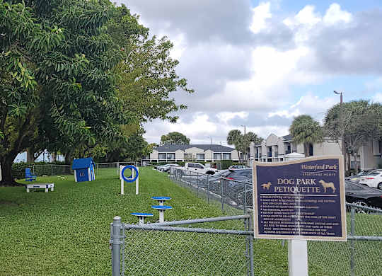 a park with a sign and chairs in the grass