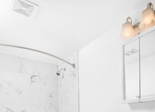 A white toilet in a bathroom with a marble wall.