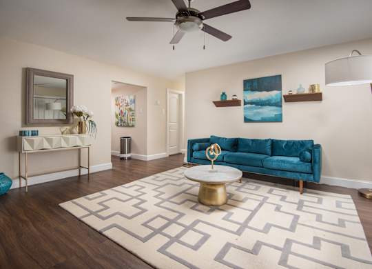 A living room with a blue couch and a patterned rug.