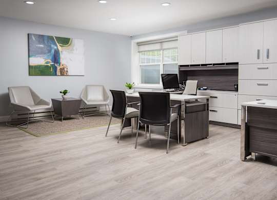A modern office space with a desk, chairs, and a painting on the wall.
