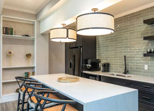 A kitchen with a white countertop and black chairs.