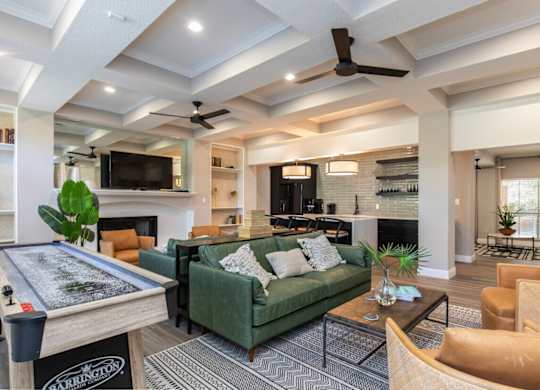 A living room with a pool table and a green couch.