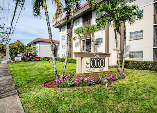 A sign for Del Oro Apartment Homes is in front of a building with a landscaped area.